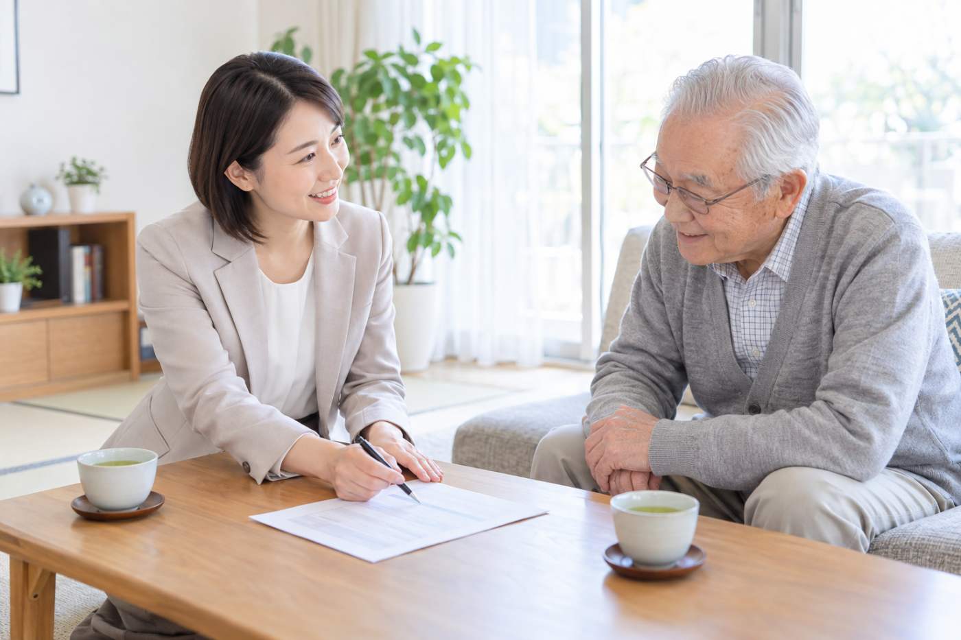 賃貸管理会社の担当者が高齢の入居者に見守りの仕組みと連絡先について説明している写真イメージ